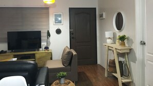 Una sala de estar con televisión, sofá y una puerta.