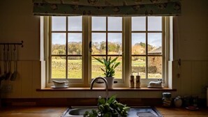 A kitchen with a large window, a sink, and a window sill with a potted plant. - Yew Tree Cottage | Farm Stay | Sleeps 4 (West Ayton)