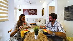 Ein modernes Wohnzimmer mit einer Couch, einem Esstisch mit Essen darauf und einem Deckenventilator.