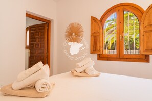 Une chambre d’hôtel avec une porte en bois, une fenêtre donnant sur des palmiers et un autocollant mural représentant une carte et du texte.