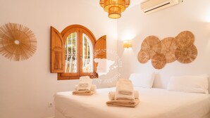 Een hotelkamer met een bed, twee handdoeken, een houten deur, een raam en decoratieve wandpanelen.