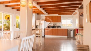 Een moderne keuken met houten balken, een centraal eiland en een eethoek met witte stoelen.