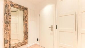A room with a stone-framed mirror, white doors, and a wooden floor. - Appartement Northland 8 (Sylt)