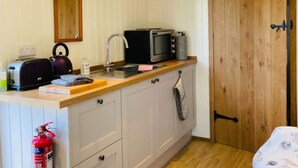 A compact kitchenette with a toaster, kettle, microwave, and sink. - Shepherds Hut | Cosy Farm Stay | Sleeps 2 (West Ayton)