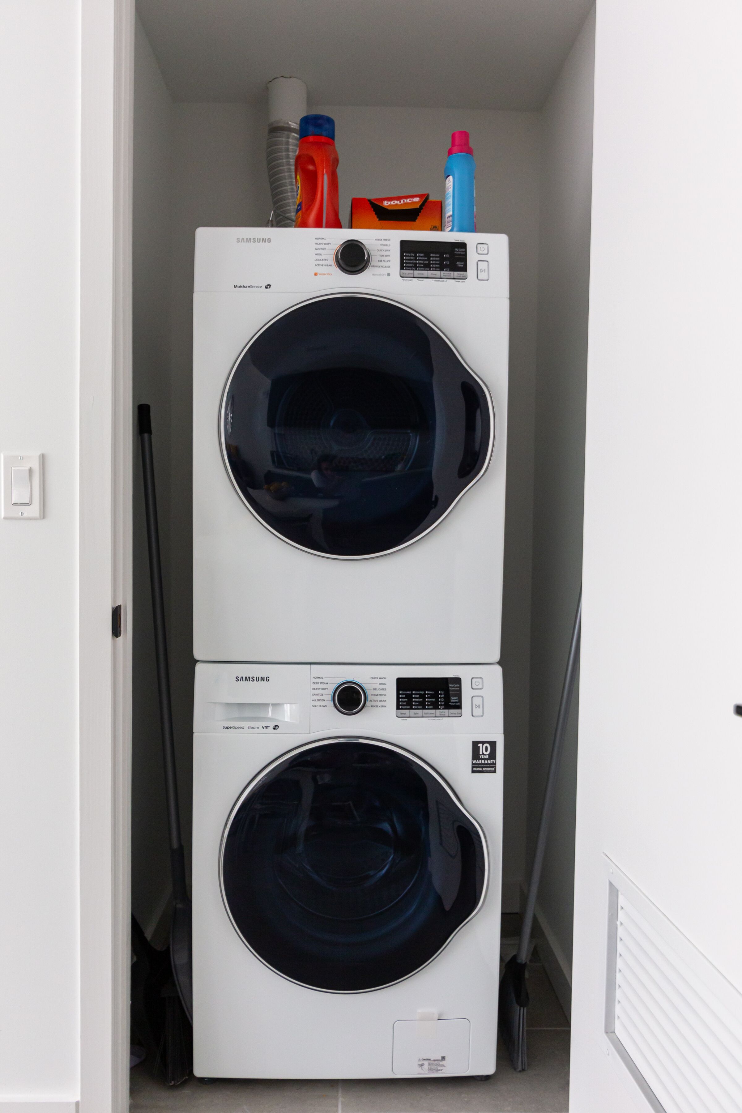 Een gestapelde wasmachine en droger in een smalle gang.