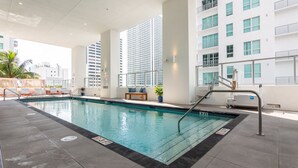 A modern indoor swimming pool with clear water, adjacent lounge area, and a view of tall buildings. - MirabileCondoDwntown MIA Brickell w PRKG (Miami)