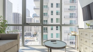 A modern living room with a large window, a sofa, a round table, and a cabinet. - MirabileCondoDwntown MIA Brickell w PRKG (Miami)