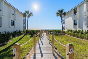 A pathway leading to a beachfront property with a clear view of the ocean.