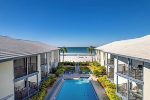 Ett hotell med en swimmingpool, utsikt över stranden och flera balkonger.