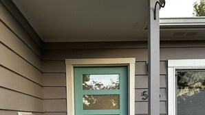 Una puerta principal color turquesa con un panel de vidrio, un buzón y un felpudo con un diseño floral.