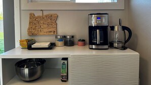 Una encimera de cocina con una cafetera, recipientes de azúcar, un mapa y una jarra de café.