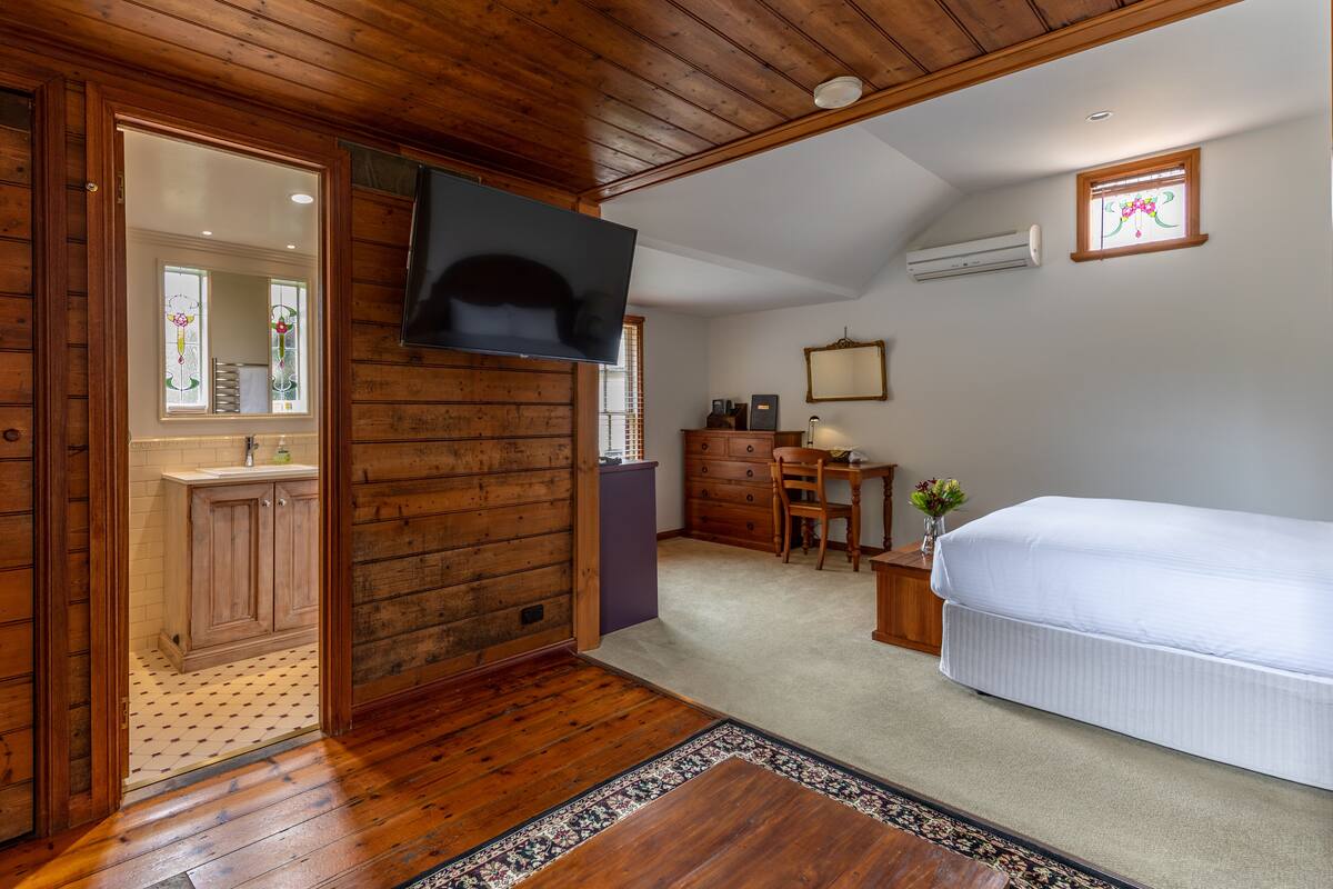 Un dormitorio con paredes de madera, un televisor de pantalla plana, una cama, un escritorio y una silla.