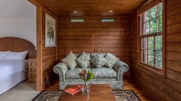 L’intérieur d’un chalet en bois, avec un lit, un canapé, une table basse surmontée d’un vase et un tableau encadré accroché au mur.