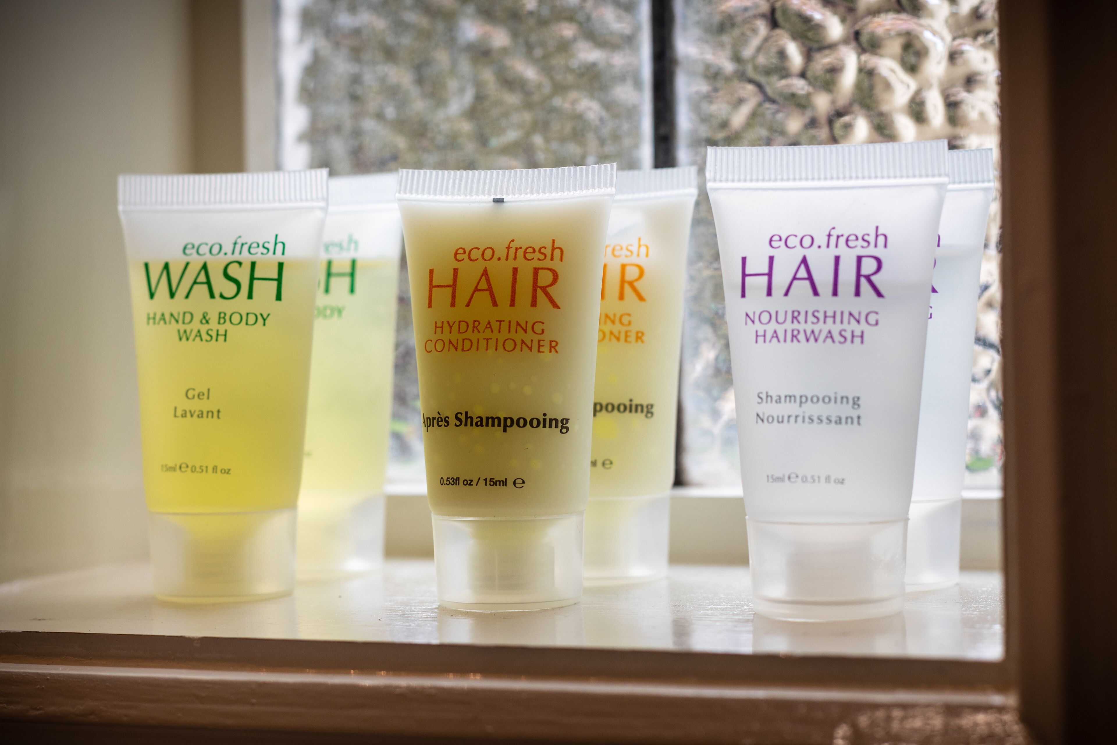 Four bottles of eco.fresh hair care products on a shelf.