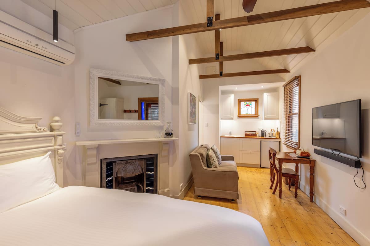 Un dormitorio con una cama grande, una chimenea, un sofá, un área de comedor con mesa y sillas, y un televisor montado en la pared.