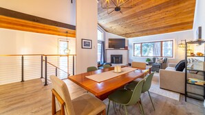 A spacious living area with a wooden dining table, green chairs, a sofa, and a fireplace. - Newly Remodeled by Eagle Lodge; Jacuzzi & Parking (Mammoth Lakes)