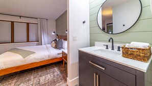 A bedroom with a bed, bedside table, and a large mirror above the sink. - Newly Remodeled by Eagle Lodge; Jacuzzi & Parking (Mammoth Lakes)