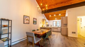A modern kitchen with wooden cabinets, a dining area with a wooden table and chairs, and a chandelier. - Newly Remodeled by Eagle Lodge; Jacuzzi & Parking (Mammoth Lakes)