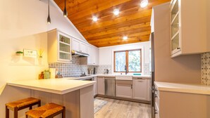 A kitchen with wooden ceiling, white cabinets, and a window. - Newly Remodeled by Eagle Lodge; Jacuzzi & Parking (Mammoth Lakes)