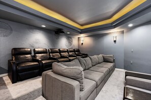A home theater room with a sectional sofa and multiple leather recliners.