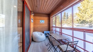 A wooden cabin with a large window, a wooden table with chairs, and a bean bag chair. - Remodeled Retreat at Eagle Lodge - Spa & Garage! (Mammoth Lakes)