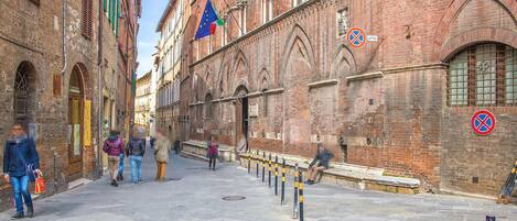 Eine historische Straße mit roten Backsteingebäuden, Kopfsteinpflaster und Fußgängern.
