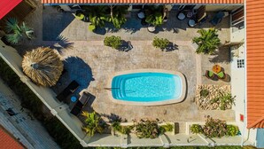 An aerial view of a swimming pool area with a tiled deck, lounge chairs, and potted plants. - Spacious 1-bed w/ courtyard near Palm Beach (Palm Beach)