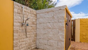A small, enclosed outdoor shower area with stone walls and a tiled floor. - Cute & Cozy 3BR, Great Location (Noord)