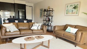 A living room with two brown leather sofas, a white coffee table, and a bookshelf. - Capel Sound Coastal Stays (Capel Sound)