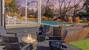 Eine Außenpatio mit Feuerstelle, Liegestühlen und Pool.