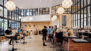 Ein modernes Café mit hohen Decken, großen Fenstern und einer zentralen Bar.