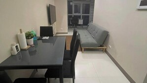 Een knus woongedeelte met een eettafel, stoelen, een bank en een televisie.