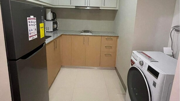 Een functionele keuken met een koelkast, magnetron, fornuis en wasmachine.