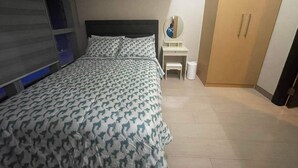 Een slaapkamer met een bed, een bureau, een spiegel en een kledingkast.
