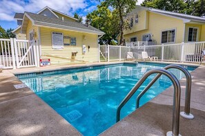 A pool area with a lifeguard station, a fenced deck, and a yellow building. - Birch Grove Cottage, Downtown Fish Creek (Fish Creek)