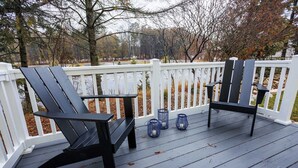 A deck with two Adirondack chairs, a white railing, and three blue lanterns. - Birch Grove Cottage, Downtown Fish Creek (Fish Creek)