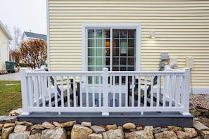 A house with a white porch, a stone foundation, and a window with blinds.