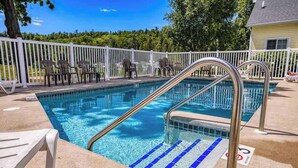 A swimming pool with a metal ladder, lounge chairs, and a white fence. - Birch Grove Cottage, Downtown Fish Creek (Fish Creek)