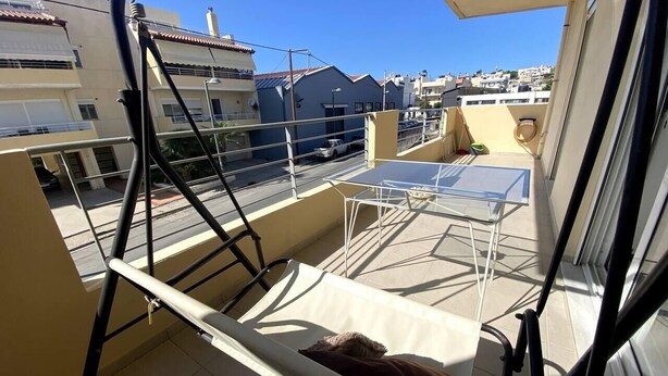A balcony with a hammock, a table, and chairs. - Impeccable Apt sleeps 5 in Heraklion (Heraklion)