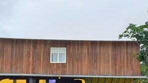 A building with a large pixelated mural on the side, a window, and a covered porch area. - Poto Mitan (Tonate-Macouria)
