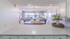 Un vaste espace de vie avec vue sur l’océan, un lustre et une table à manger avec des chaises.