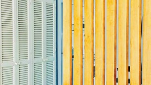 Una habitación con contraventanas blancas y un separador de madera con listones.