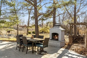 Une terrasse extérieure avec une cheminée en pierre, une table à manger et des chaises.