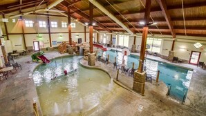 An indoor swimming pool with multiple lanes, seating areas, and a slide. - Home Sweet Log (Wisconsin Dells)