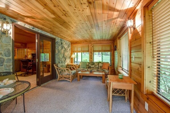 A cozy cabin interior with a stone wall, wooden ceiling, and a dining area with a table and chairs. - Home Sweet Log (Wisconsin Dells)