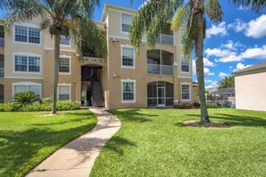 Stunning multi-story building with a central entrance and large windows, surrounded by lush greenery and palm trees.