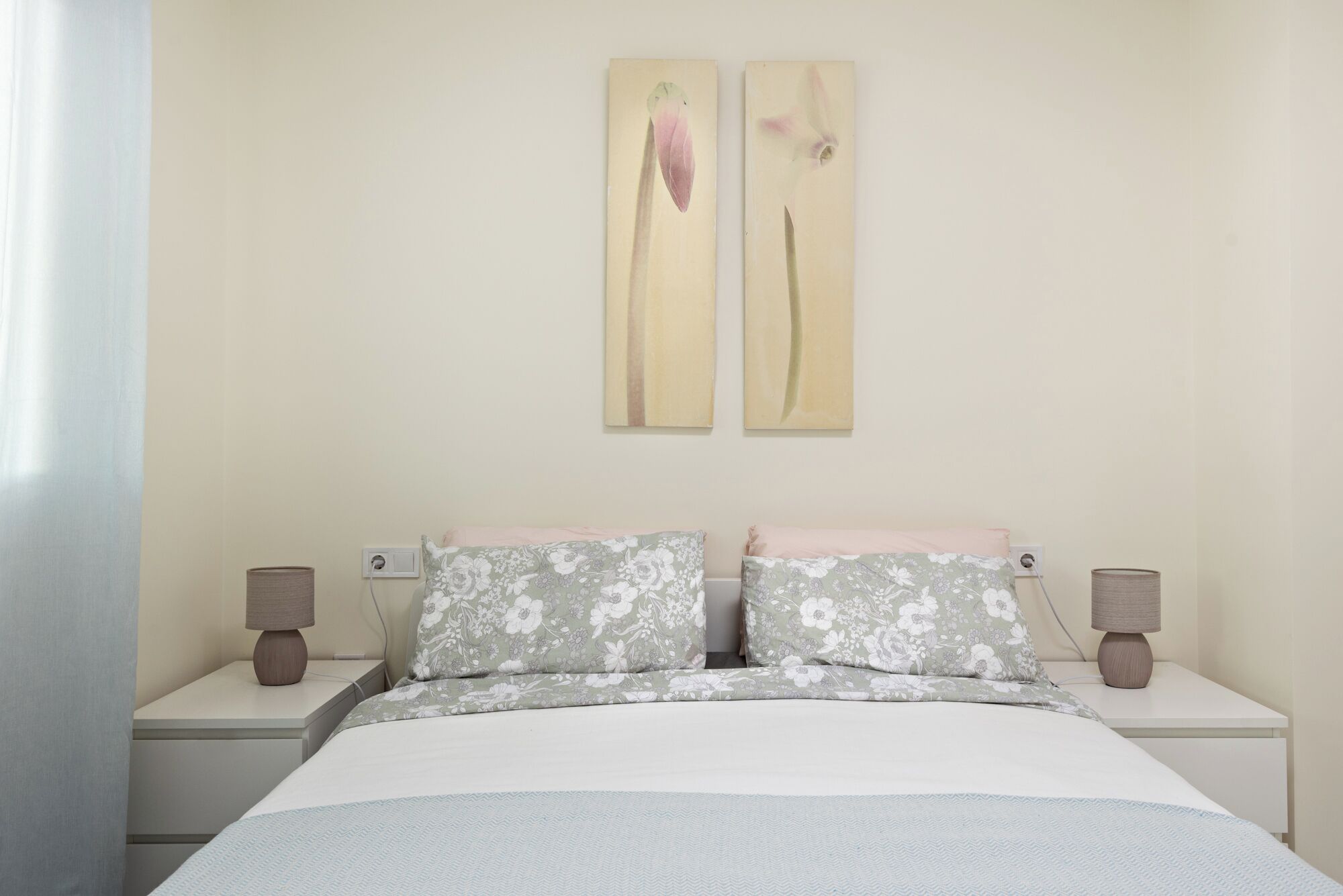 Ein Schlafzimmer mit einem Bett, zwei Nachttischen, einer Lampe und zwei an der Wand befestigten Bildern.