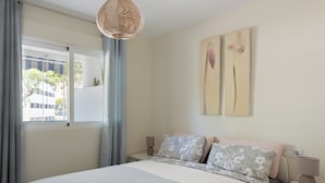 Un dormitorio con cama, cortinas, una ventana y decoración en la pared.