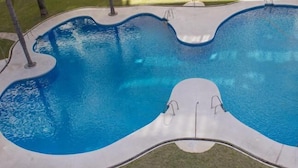 Una piscina con diseño de borde ondulado y dos escaleras.