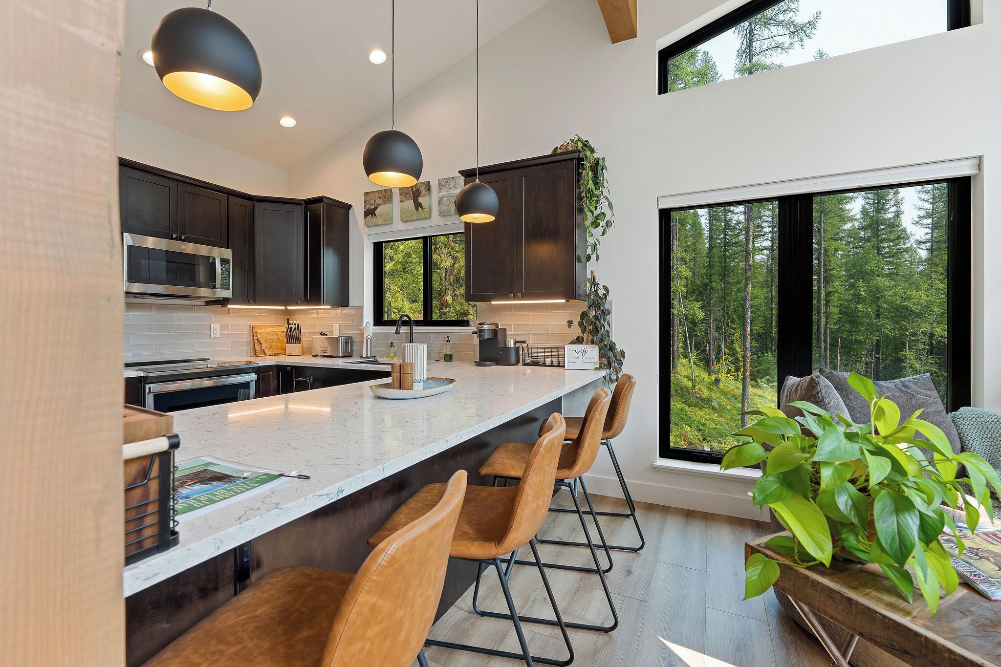Una cocina moderna con armarios oscuros, una isla grande con taburetes de bar e iluminación colgante.